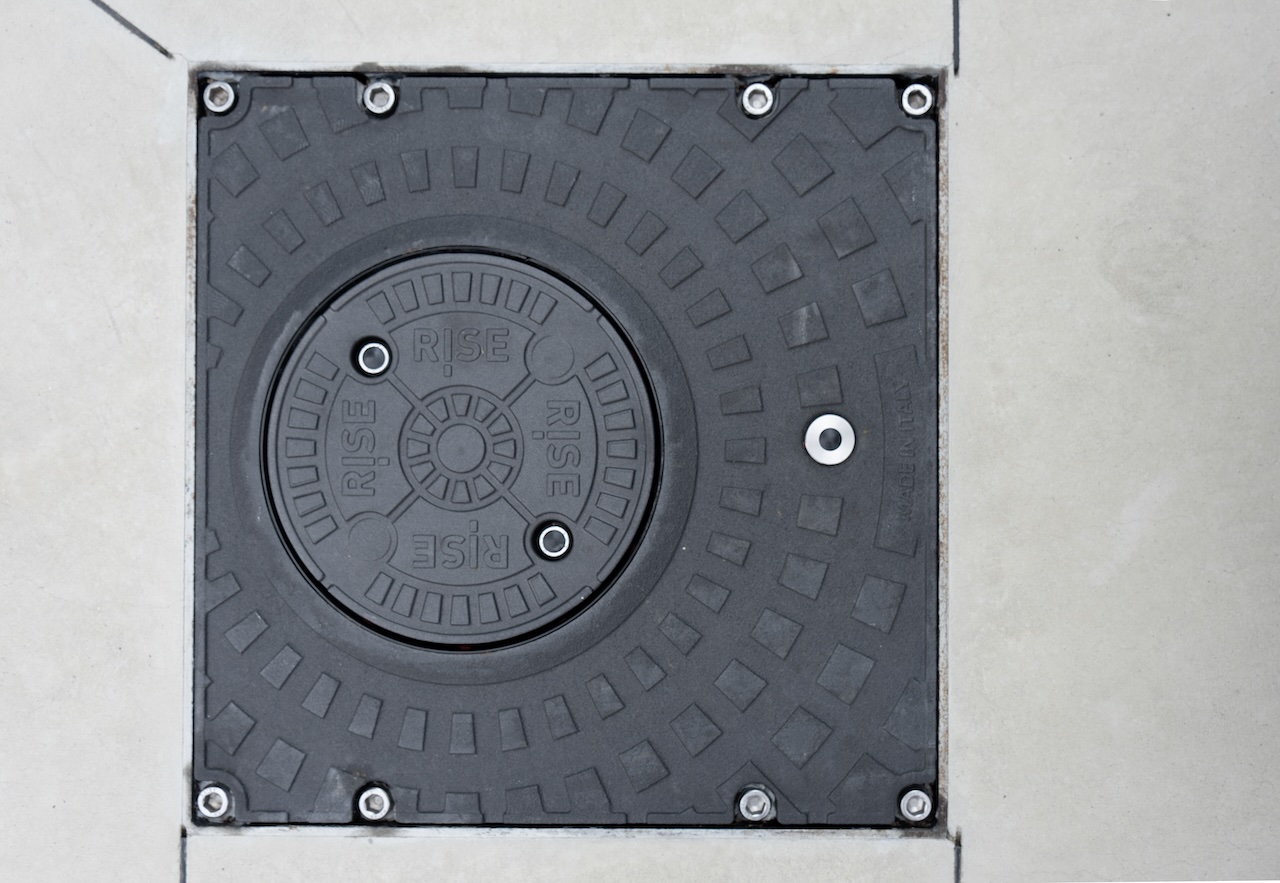 Dettaglio dall'alto di un dissuasore abbassato che protegge l'ingresso al cancello della ferramenta con magazzino